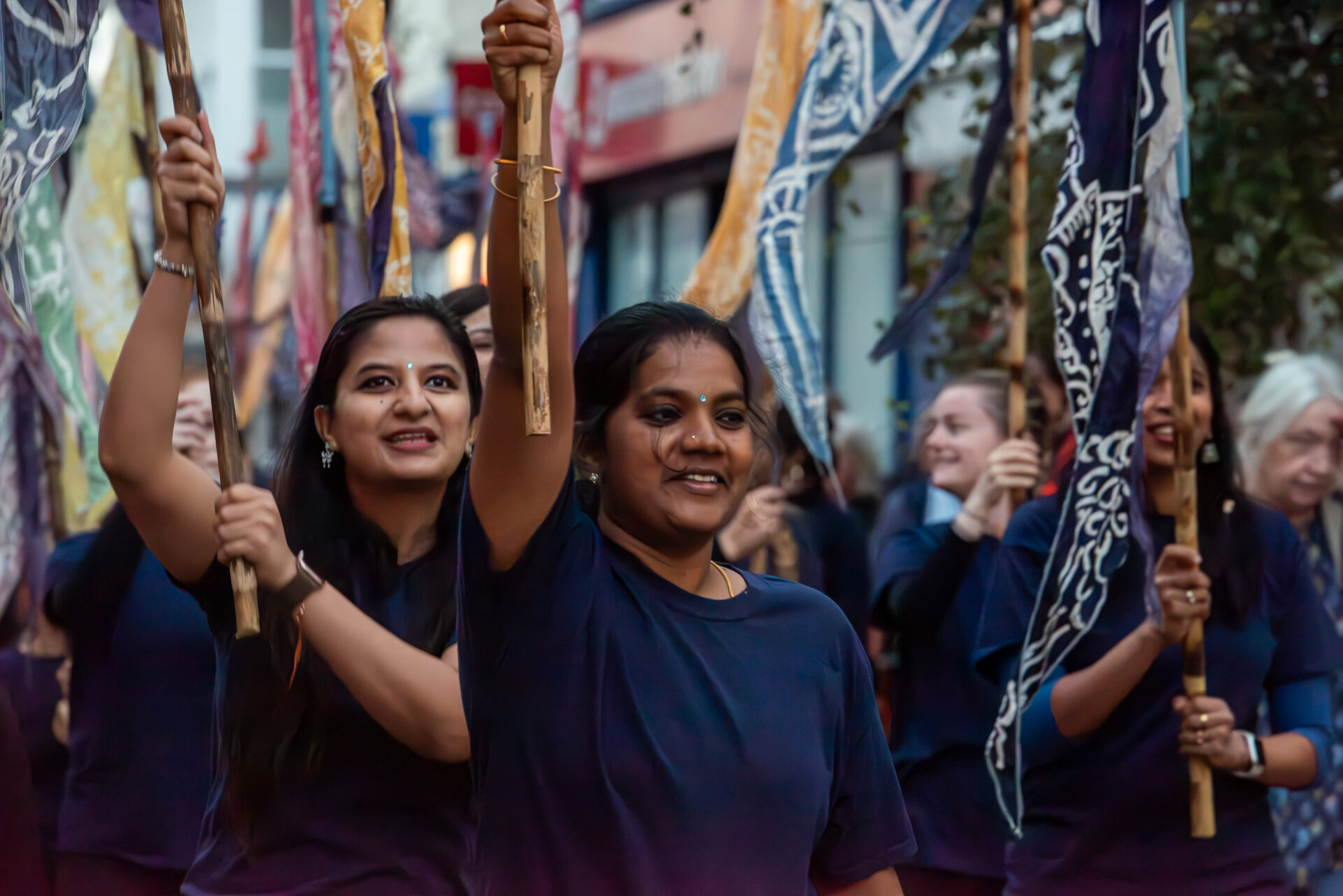 Women of Indian heritage, wearing blue tshirts and holding flags above their heads