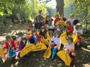 Group of school children and a woman stand in a wooded area