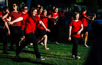 Group of young people wearing back and red, dancing on grass