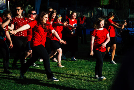 Group of young people wearing back and red, dancing on grass
