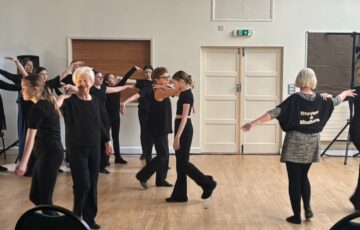 Young and old female dancers circle a room