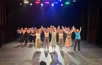 Lots of young people on a stage. 6 are near the front taking a bow.