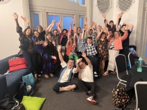 A large group of young people posing for the camera with their hands up, celebrating.