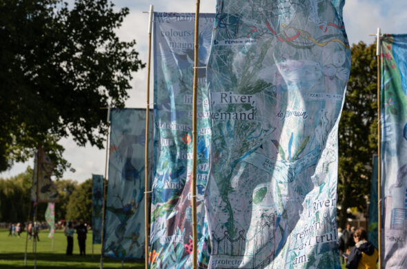 Several large flags blowing in the wind, trees in the background.