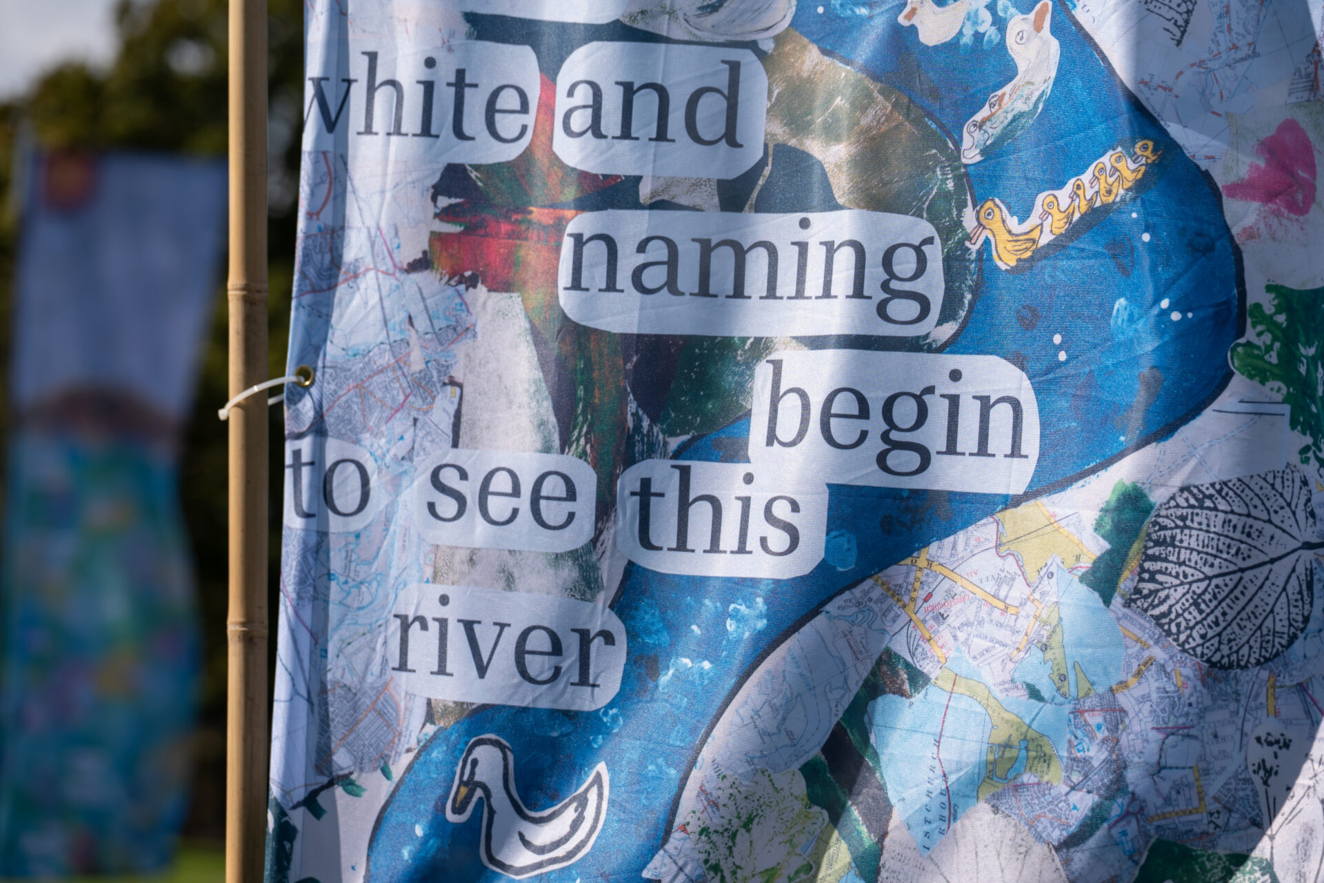 Close up of a large blue flag with text on that says 'white and naming begin to see this river'