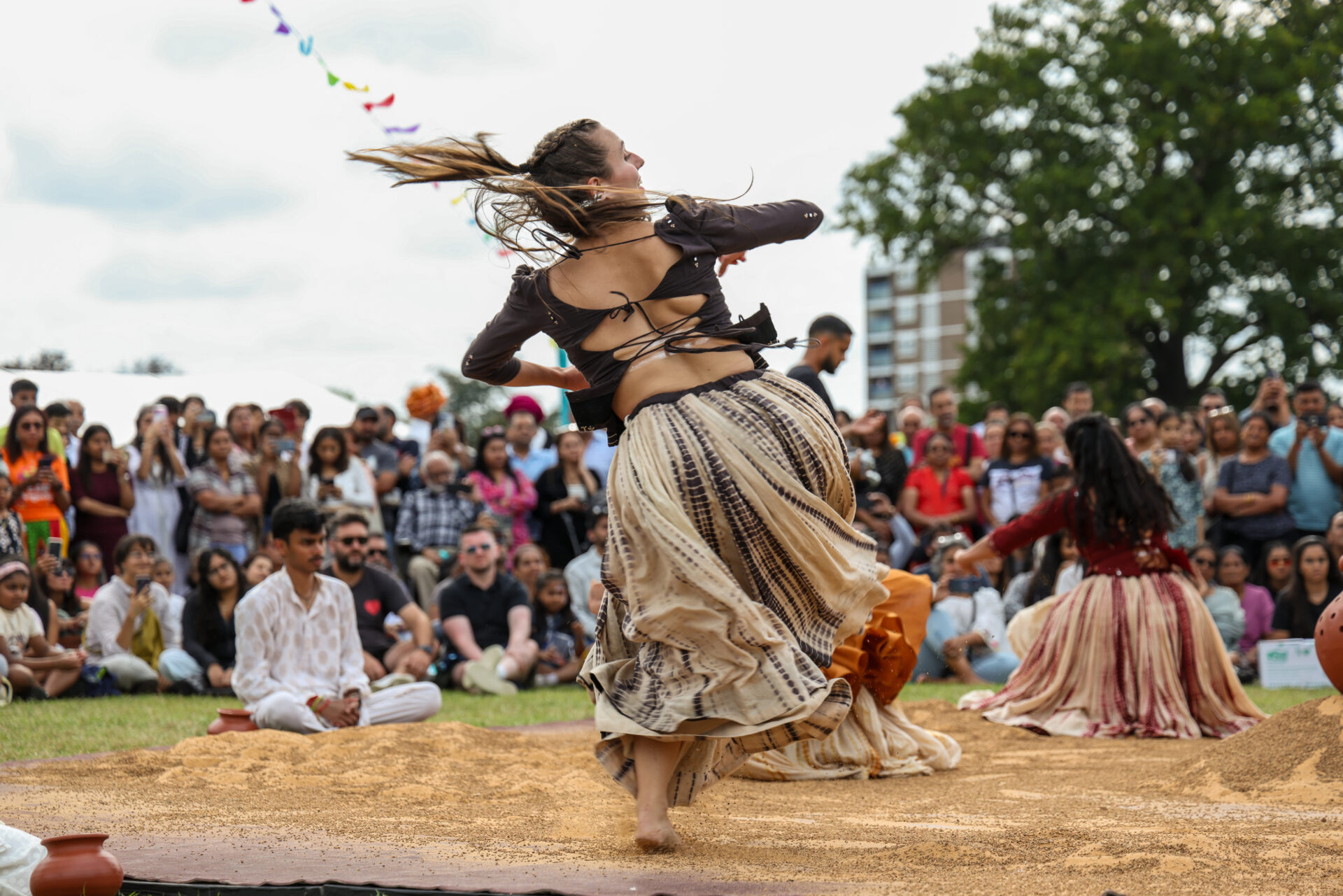 Back of a woman performing Indian dance to a crowd in front of her