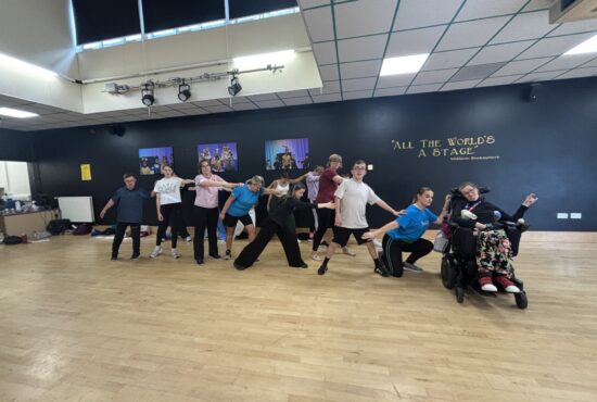 A group of dancers create a line and lean on one another