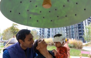 A man, woman and child are looking up at a large green dome