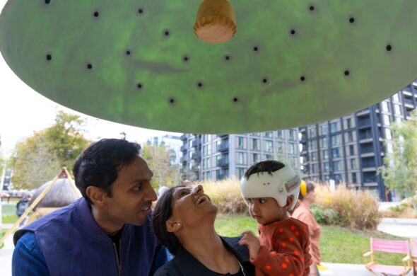 A man, woman and child are looking up at a large green dome